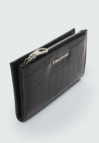 Portefeuille noir en relief crocodile avec fermeture à glissière et quincaillerie argentées, présentant une forme rectangulaire et une surface texturée. Design élégant, taille compacte.
