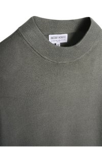 Suéter verde oliva con cuello acanalado, confeccionado en una suave mezcla de viscosa. Presenta un corte slim y una etiqueta con la marca "Antony Morato".