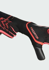 Black and red goalkeeper gloves featuring a textured grip surface, flexible material, a snug fit, and "PREDATOR" branding on the wrist cuff.