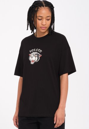 Camiseta de algodón negra con mangas cortas y un corte holgado, que presenta un gráfico de tigre bordado y el texto "VOLCOM" arriba.