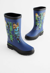 Siniset kumisaappaat, joissa on teksturoitu musta pohja ja värikkäitä Minecraft-hahmografiikoita sivuilla, sekä musta reunus yläosassa.