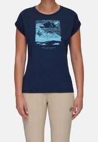 Camiseta de manga corta azul marino con un estampado gráfico de montaña en azul claro. Fabricada con una tela suave, tiene un corte relajado y mangas enrolladas.