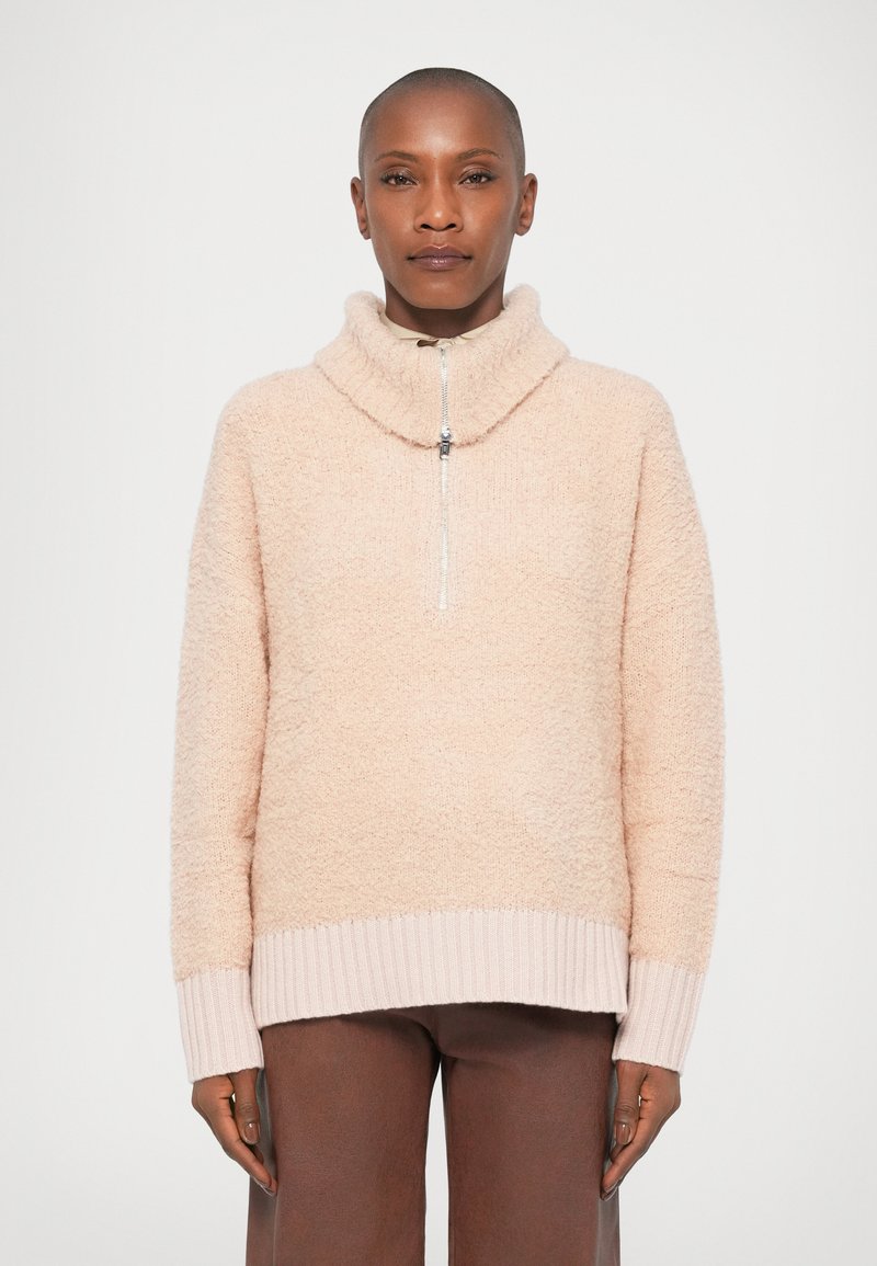 Maglione pullover rosa chiaro e morbido con colletto alto e zip a quarto; polsini e orlo a coste, texture soffice, vestibilità rilassata.