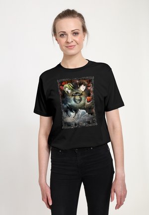 T-shirt en coton noir présentant une impression graphique avec des personnages d'anime encadrés par une bordure décorative. Encolure ronde et manches courtes.