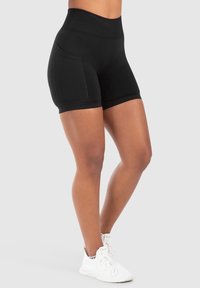 Leggings noires courtes avec une taille haute élastique et des poches latérales. Fabriqués en tissu extensible, conçus pour le confort et la mobilité.