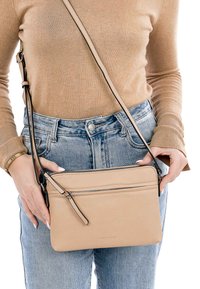 Borsa a tracolla in pelle beige con tracolla regolabile, dotata di una texture liscia, di una tasca con zip e di una semplice forma rettangolare.