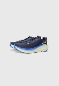 Scarpe sportive blu navy con tomaia texturizzata, controgetto rigido e una suola spessa in gradiente blu e bianco. Presentano lacci piatti e dettagli riflettenti.
