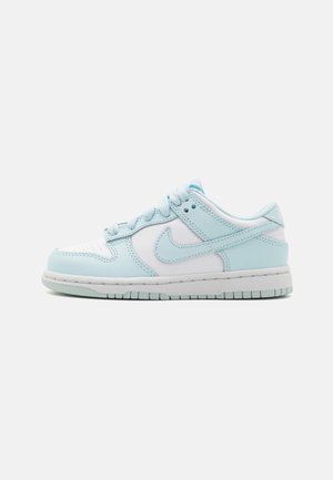 Lys blå og hvid Nike-sneaker med en glat læderoverdel, perforeret tå og teksturerede elementer; har flade snørebånd og gummisål.