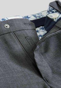 Dunkelgraue Jacke mit einem Reißverschluss vorne und Knopfverschluss, ausgestattet mit einem gemusterten Innenkragen. Enthält ein Markenetikett und einen strukturierten Stoff.
