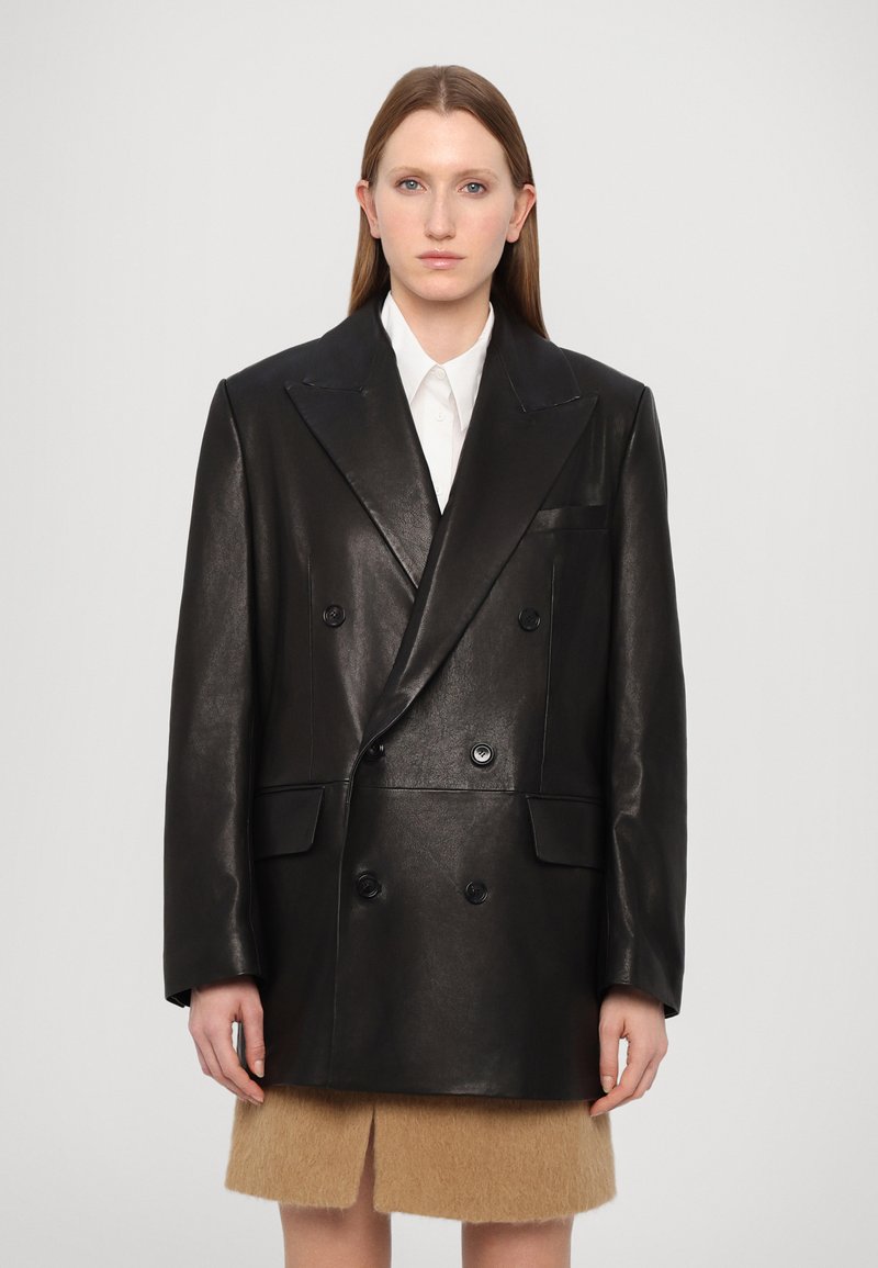 Melnas ādas dubultā josta ar izgrieztu apkakli, divām priekšējām kabatām un plecu ieliktņiem; kombinēta ar beigtu kažokādu minilentu.