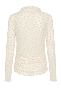 Garām piedurknēm topi krēmkrāsā ar smalku ziedu rakstu gaiši bēšā krāsā. Sānos ir savilkumi un mīksts, teksturēts audums.