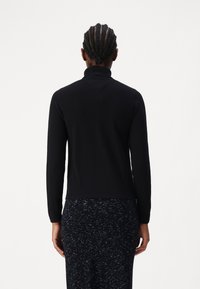 Melnā ar gariem piedurknēm, turtlenecks džemperis ar pieguļošu dizainu un rievotu tekstūru. Gluda auduma virsma ar maigu spīdumu un taisnu apakšmali.