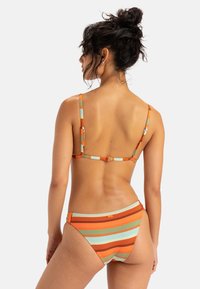 Randig bikini med färgerna orange, blå och brun. Ribbstruktur. Justerbara spaghetti-remmar och en låg midje-design.