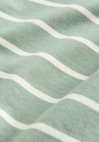 Hele roheline kangas, millel on horisontaalsed valged triibud, pehme tekstuur ja veidi tekstureeritud kootud muster.