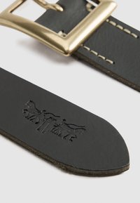 Cinturón de cuero negro con hebilla rectangular de metal en tono dorado. La correa presenta detalles en relieve a lo largo del borde.