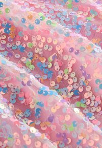 Tissu en maille rose recouvert de sequins ronds irisés multicolores, disposés densément sur toute la surface.