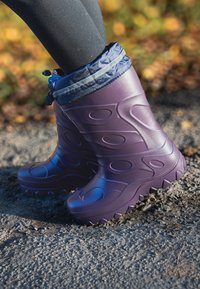 Paarse rubberen regenlaarzen met een gestructureerd oppervlak, cirkelvormige patronen en een gevoerde rand. Voorzien van een blauw trekkoord voor verstelbaarheid.