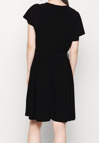 Svart kortärmad klänning med figurnära bodice, elastisk midja och fladdrande kjol; slät textur, minimal design och inga synliga mönster.