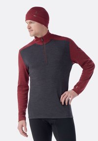 Donkere grijze longsleeve pullover met rode raglanmouwen, voorzien van een ritssluiting bij de kraag en logo-accenten op de borst en mouw.