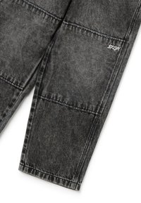 Pantalones de mezclilla negros con un acabado desgastado, que cuentan con costuras visibles, una etiqueta de marca y un diseño de pierna recta.