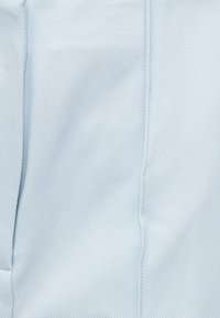 Υφασμα σε ανοιχτό γαλάζιο με υφή, κάθετη ραφή και διακριτικές π τυχές, εμφανίζοντας στενή λήψη του υλικού ενδύματος και λεπτομέρειες ραφής.