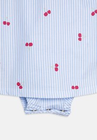 Niebiesko-biała tkanina w paski z haftowanymi czerwonymi wiśniami. Zapięcia na zatrzaski na dole ułatwiające zakładanie. Lekki materiał bawełniany.