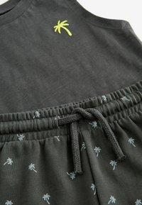 Dunkelgraues ärmelloses Shirt mit grüner Palmbaumstickerei; passende Shorts mit Kordelzug und hellgrauem Palmbaumdruck auf der gesamten Oberfläche.