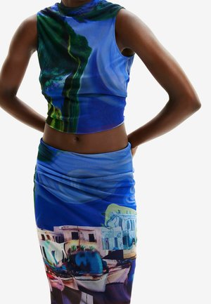 Niebieski top bez rękawów i dopasowana spódnica z nadrukiem miasta nadmorskiego i łodzi, noszone przez osobę z rękami za plecami.