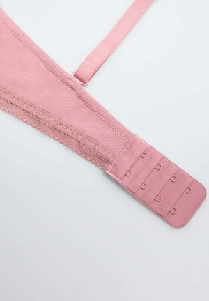 Sostén inalámbrico rosa que presenta una tela suave y texturizada, bordes con forma de ola, tirantes ajustables y un cierre de gancho y ojal con cuatro filas.