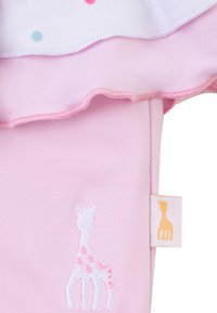 Completo per bambini rosa con orlo arricciato, composto da una maglietta bianca con pois blu e rosa, e un ricamo di giraffa sui pantaloni.
