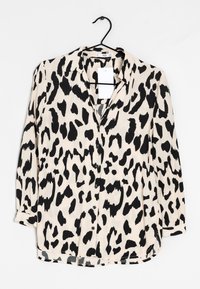 Camicia button-up beige con stampa leopardata nera. Presenta un colletto, maniche lunghe e un orlo dritto con una vestibilità rilassata.