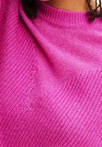 Fuksiankirkas neulepaita, jossa on resorikuvio ja pyöreä pääntie. Hienovaraiset kuviot korostavat pehmeää, kevyttä materiaalia.