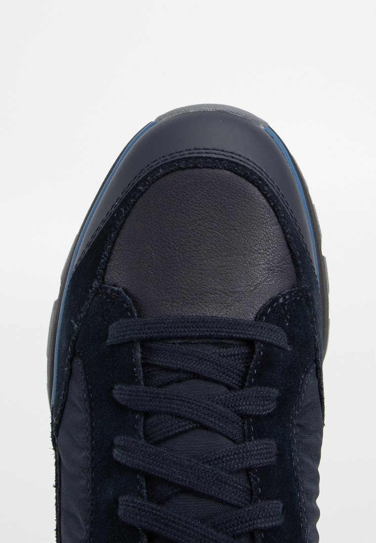 Granatowe sneakersy wykonane z połączenia skóry i zamszu, o teksturowanej powierzchni, zaokrąglonym nosku, płaskich sznurówkach i gumowej podeszwie.