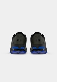 Črne in sive Nike superge z teksturirano zgornjico, ki imajo moderen gumijast podplat, vidno blazinjenje in logotipne dodatke na petah.