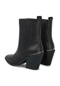 Botas de piel negra hasta el tobillo con paneles laterales elásticos, punta afilada y tacón grueso. Presentan una silueta elegante y acentos metálicos en el tacón.