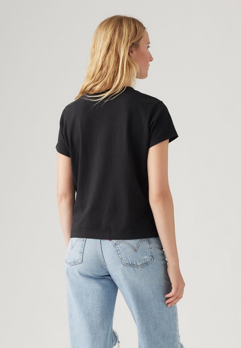 Czarny krótki t-shirt z okrągłym dekoltem, wykonany z miękkiej bawełny, zestawiony z jasnoniebieskimi jeansami z przetarciami.