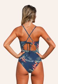 Costume da bagno intero blu navy con stampa floreale tropicale, spalline incrociate regolabili, schiena scoperta e dettaglio con fiocco in vita.