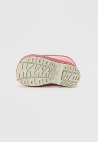 Shoe rosa com uma sola espessa e texturizada em off-white. Apresenta um design curvo e um padrão de aderência distinto para mais tração. Material leve.