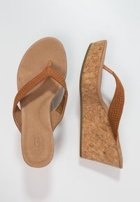 Hnědé klínové sandály s korkovým podpatkem, strukturovanými hnědými popruhy a hladkým koženým stélkou. Mají otevřenou špičku a minimalistický design.