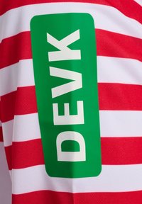 Chemise rayée rouge et blanche avec un tissu texturé, présentant un grand rectangle vert avec le texte blanc "DEVK" en évidence.