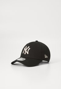 Schwarze Baseballmütze mit einem beigen New York Yankees-Logo. Verfügt über eine strukturierte Passform, einen gebogenen Schirm und einen verstellbaren Schnellverschluss im Rücken.