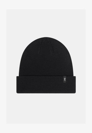 Gorro de punto negro con dobladillo, que presenta una pequeña etiqueta de logo blanca en el lado. Textura suave y ajuste redondeado ceñido.