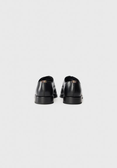 Scarpe in pelle nera con una finitura liscia, punta rotonda, tacco basso e dettagli a striscia colorati sul retro. Suola piatta, design minimal.