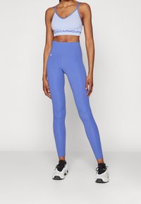 Lichtblauwe sportbeha met logo-band, gecombineerd met high-waisted, aansluitende blauwe leggings. Geweven stof, slank ontwerp.