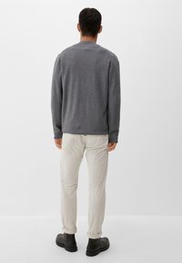 Maglione grigio a maglia con collo rotondo, abbinato a pantaloni chiari e stivali neri, con un design semplice e una texture morbida.