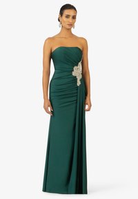 Abito senza spalline in verde smeraldo con ruching testurizzato, caratterizzato da un'elegante decorazione argentata in vita e una gonna fluente.