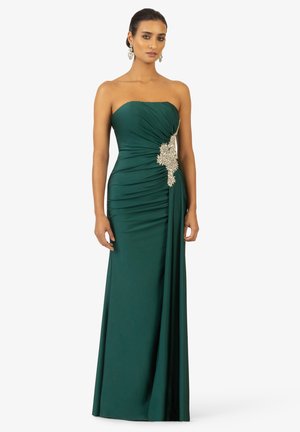 Strapless emerald gown with textured ruching, featuring a decorative silver embellishment at the waist and a flowing skirt.