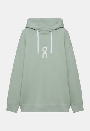 Felpa verde chiaro con cappuccio, coulisse bianche e logo stilizzato bianco al centro del petto, esposta su uno sfondo uniforme.