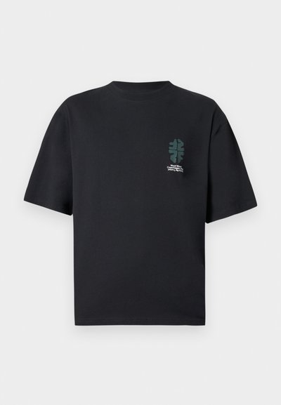 Μαύρο T-shirt με κοντά μανίκια, μικρό πράσινο αφηρημένο γραφικό φύλλο και λευκό κείμενο στο αριστερό στήθος.