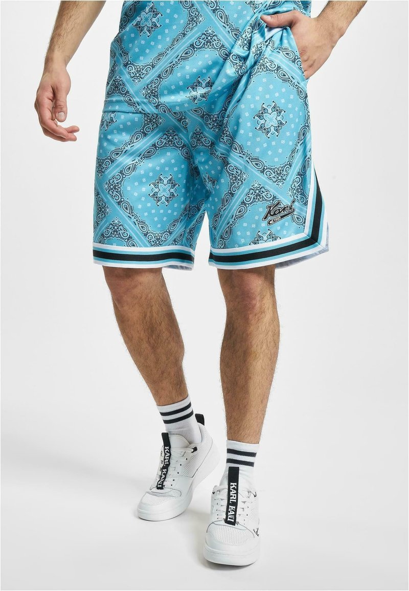 Light blue shorts with a bandana pattern, featuring black and white striped accents, side pockets, and branded detailing on the lower hem.